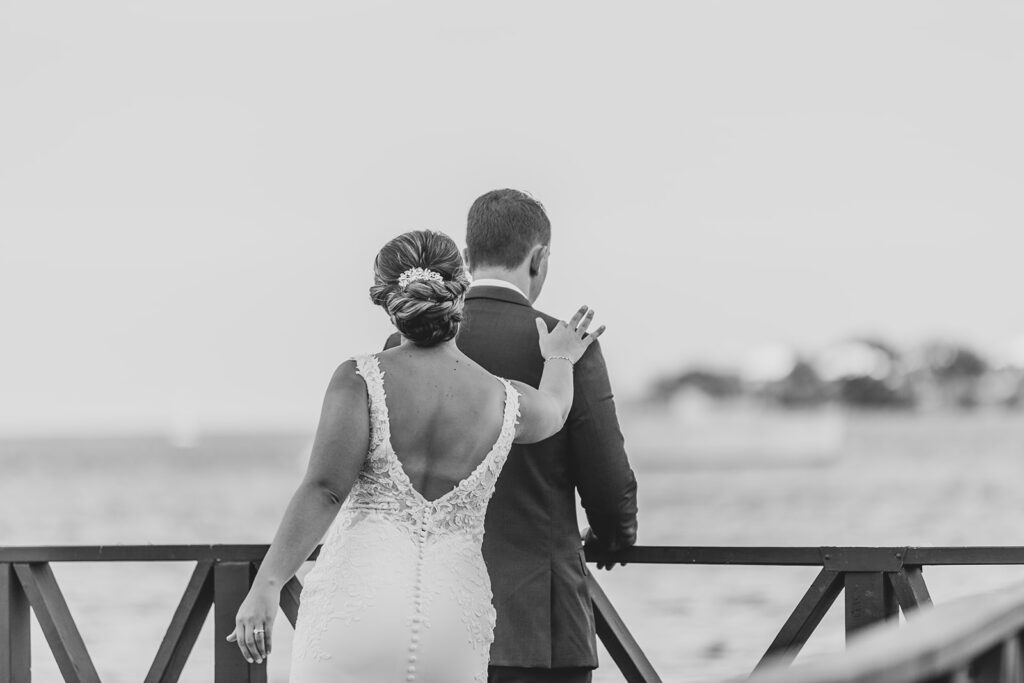 Black and white photo of the bride approaching the groom from behind to tap his shoulder for their first look.