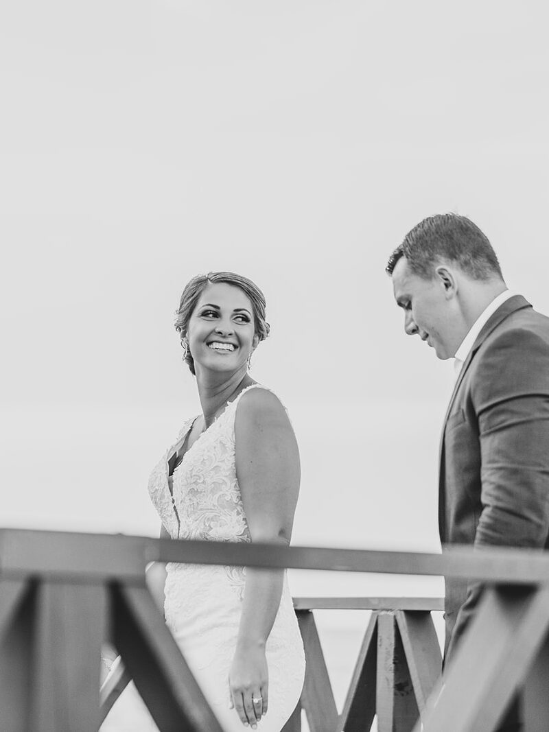 Black and white candid of the bride smiling up at the groom as they walk together after the first look.