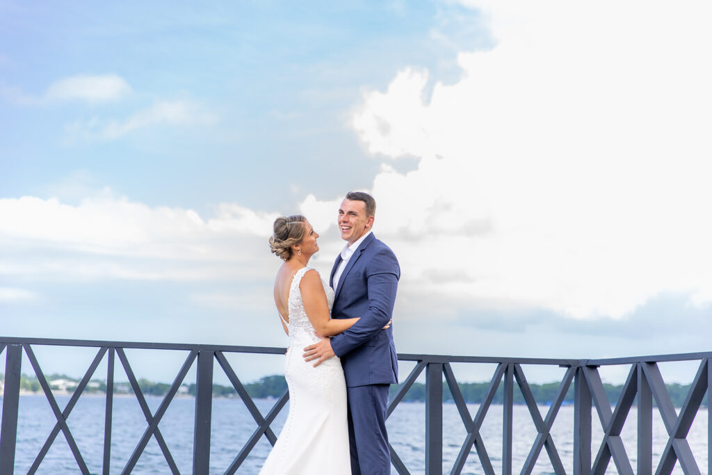 Bride and groom laughing together on the dock at Royalton Negril with the ocean and sky behind them.