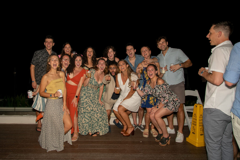 Large group of friends posing together at the outdoor welcome reception in Jamaica at night.