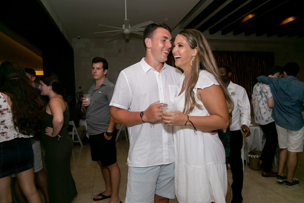 Couple laughing and holding drinks during their pre-wedding reception at Royalton Negril Resort.