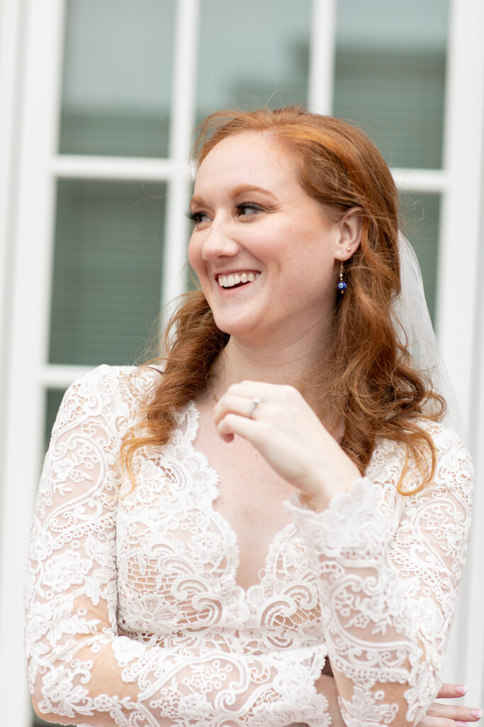 Bride smiling with her arms crossed, wearing a lace long-sleeve gown.