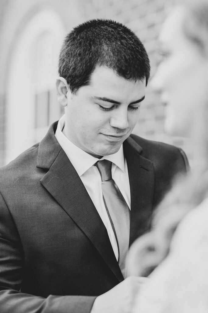 Groom looking down and holding the bride’s hands during their courthouse elopement.