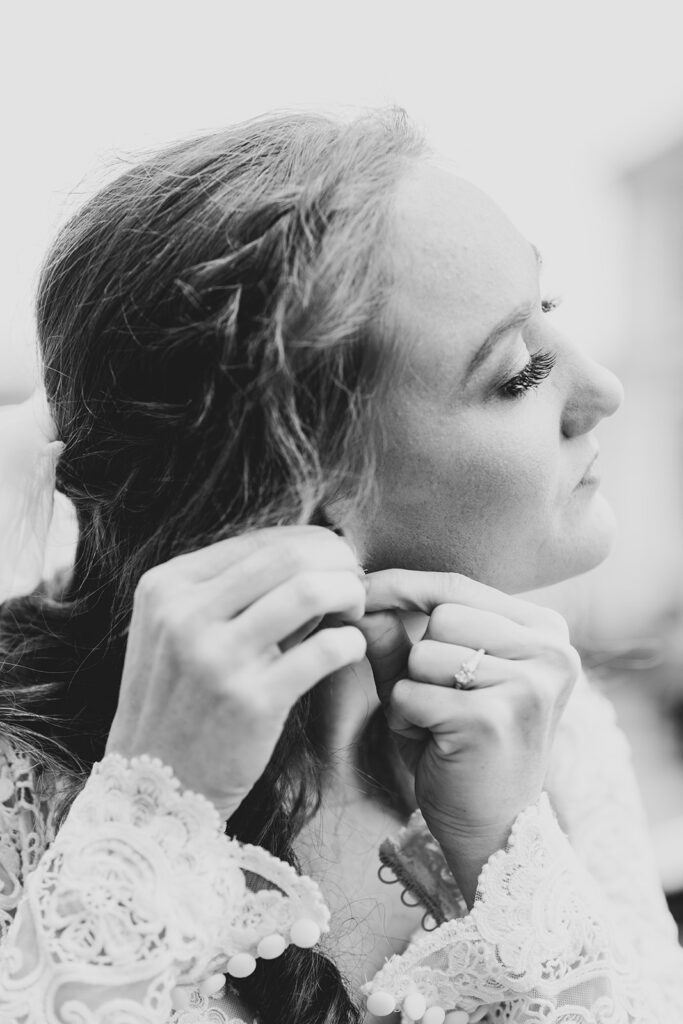 Bride adjusting her earring while getting ready outside the Fredericksburg courthouse.