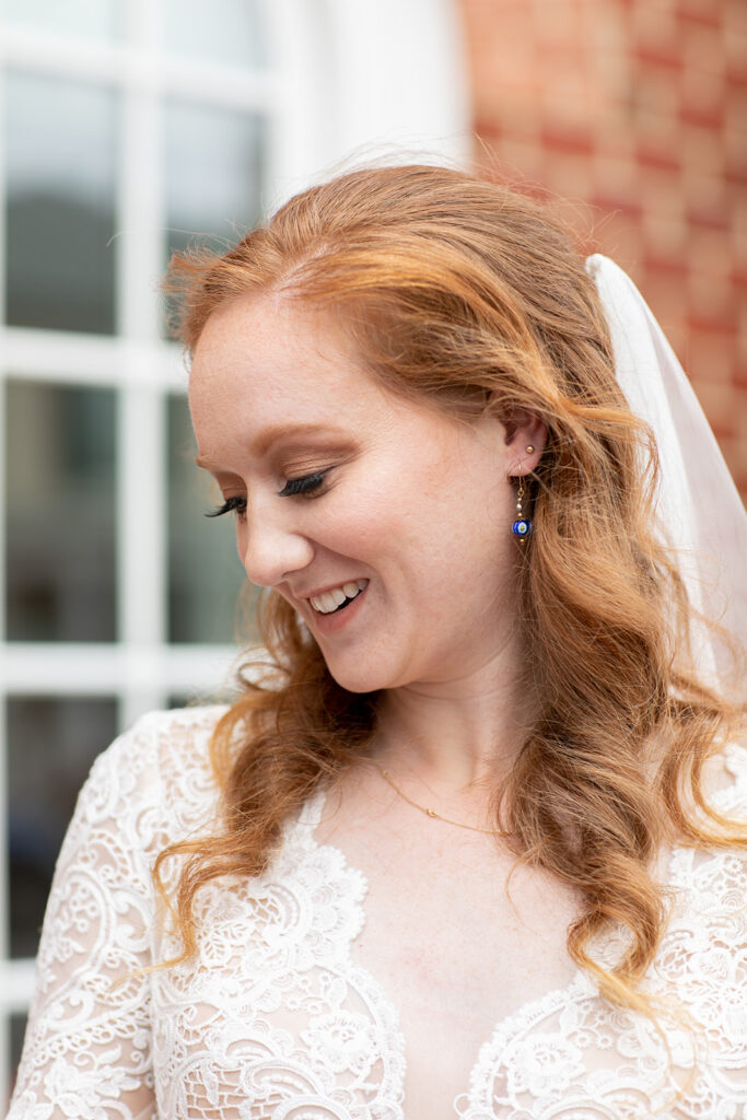 Bride smiling softly with her veil draped over her shoulder in downtown Fredericksburg.