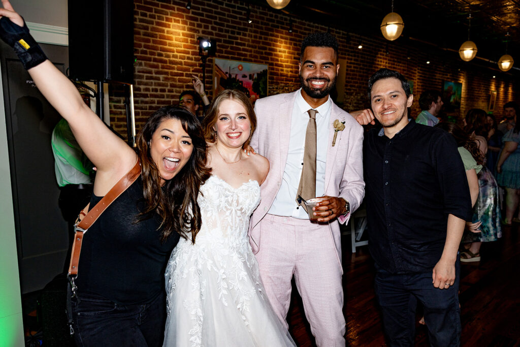 Wedding photographer and videographer team celebrating with couple during reception