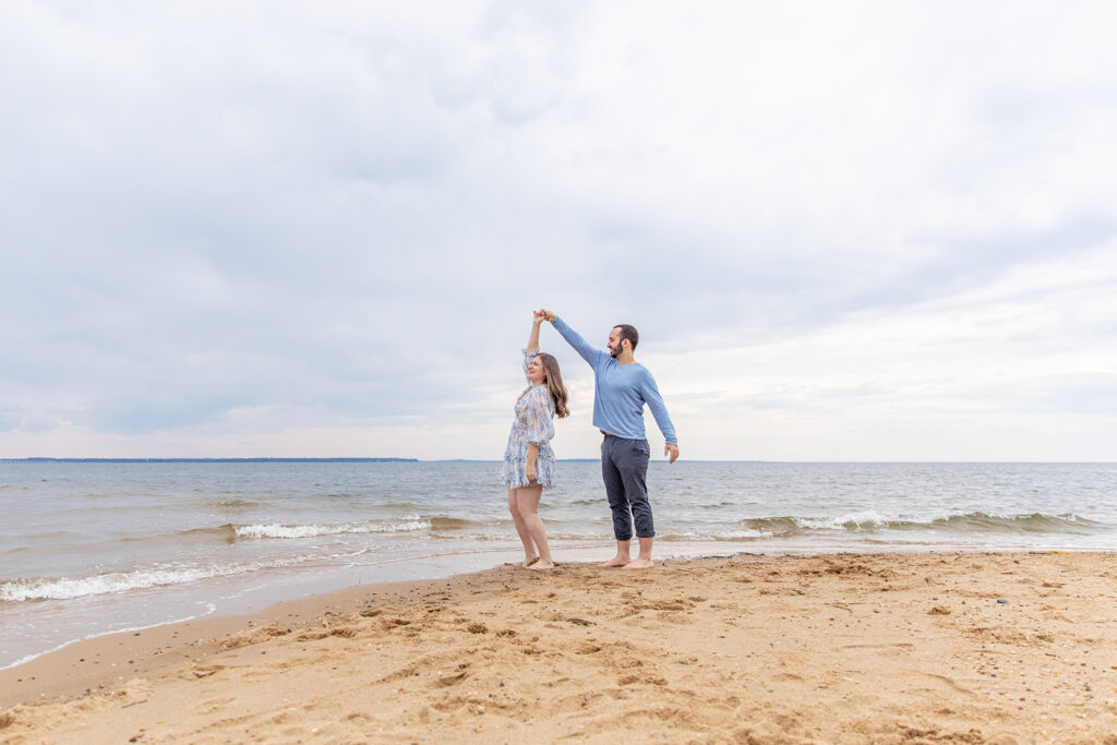 Romantic beach engagement photos near DC with a couple dancing along the bay at Terrapin Nature Park