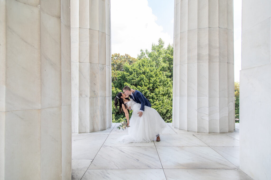 Groom dipping bride between Lincoln Memorial columns after DC elopement