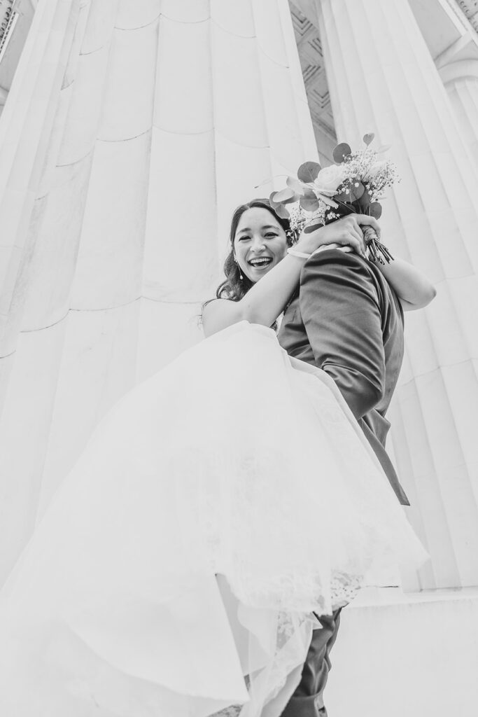 Groom picking up bride on the steps of the Lincoln Memorial