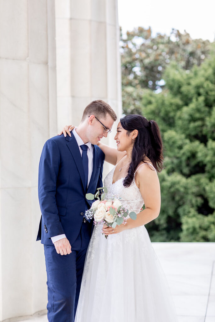 Bride and groom standing together beneath Lincoln Memorial columns during DC elopement