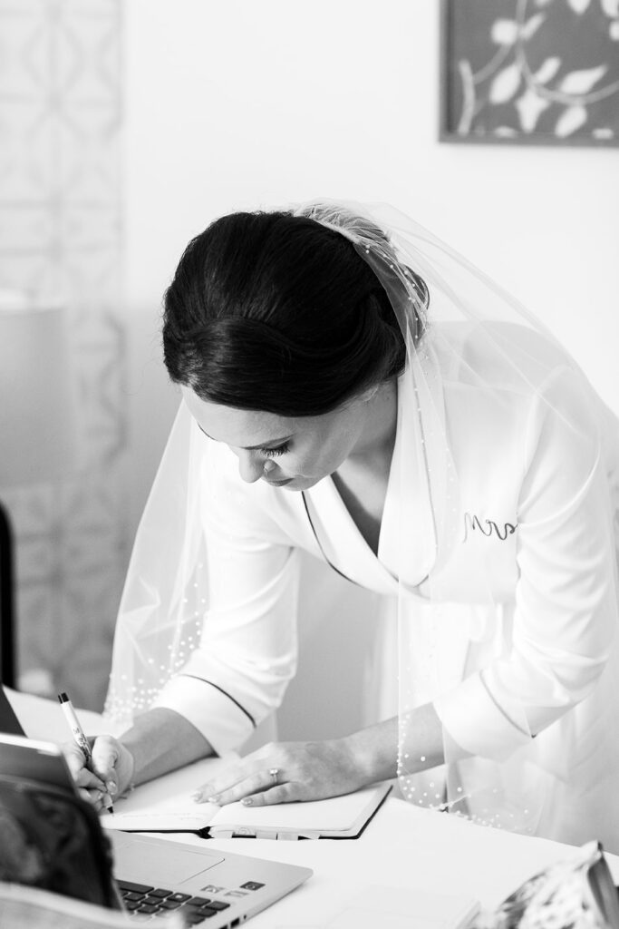 Bride hand writing her vows while getting ready with close friends during Jodi and Stu’s intimate wedding in Alexandria, Virginia.