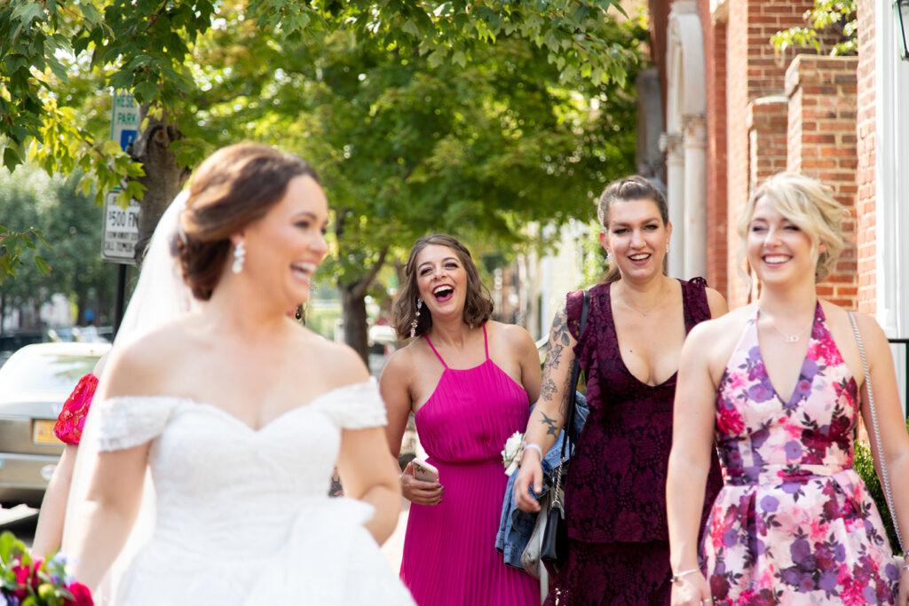 Bride laughing with close friends while walking through Old Town Alexandria during an intimate wedding day.