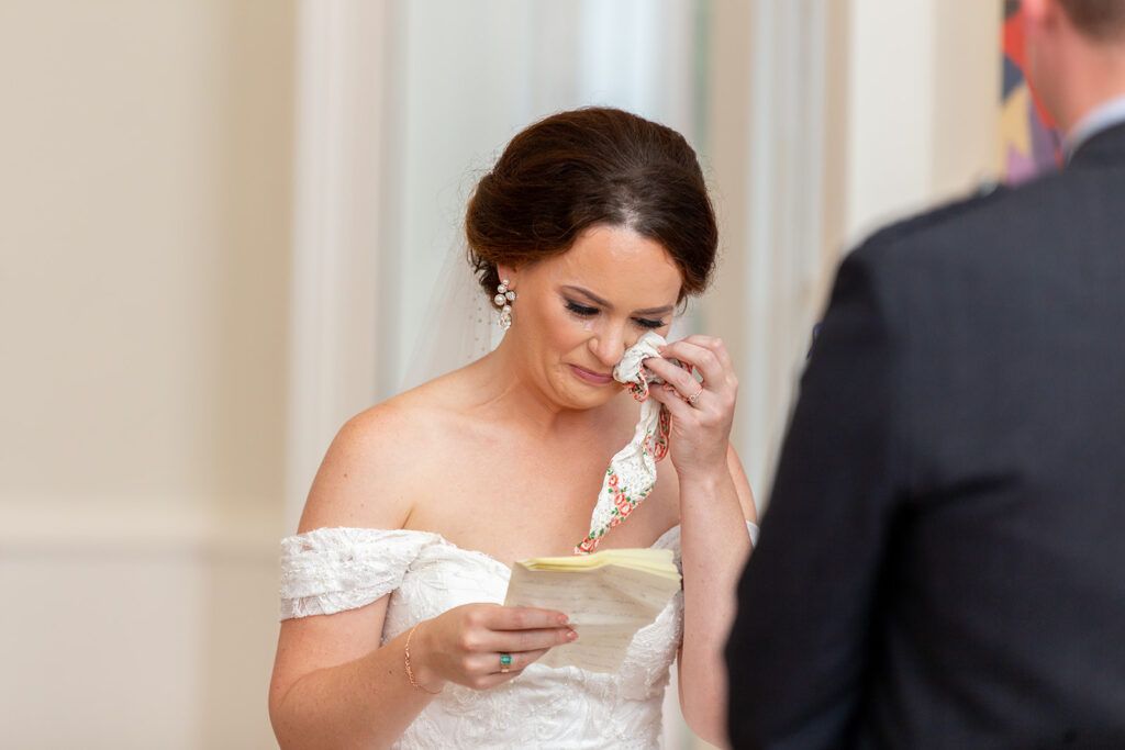 Bride wiping away tears during an emotional wedding ceremony at the Athenaeum in Alexandria.