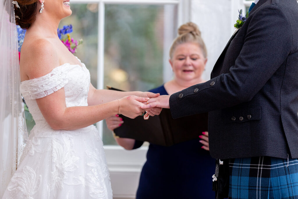 Bride and groom exchanging rings during their intimate wedding ceremony at the Athenaeum in Alexandria.