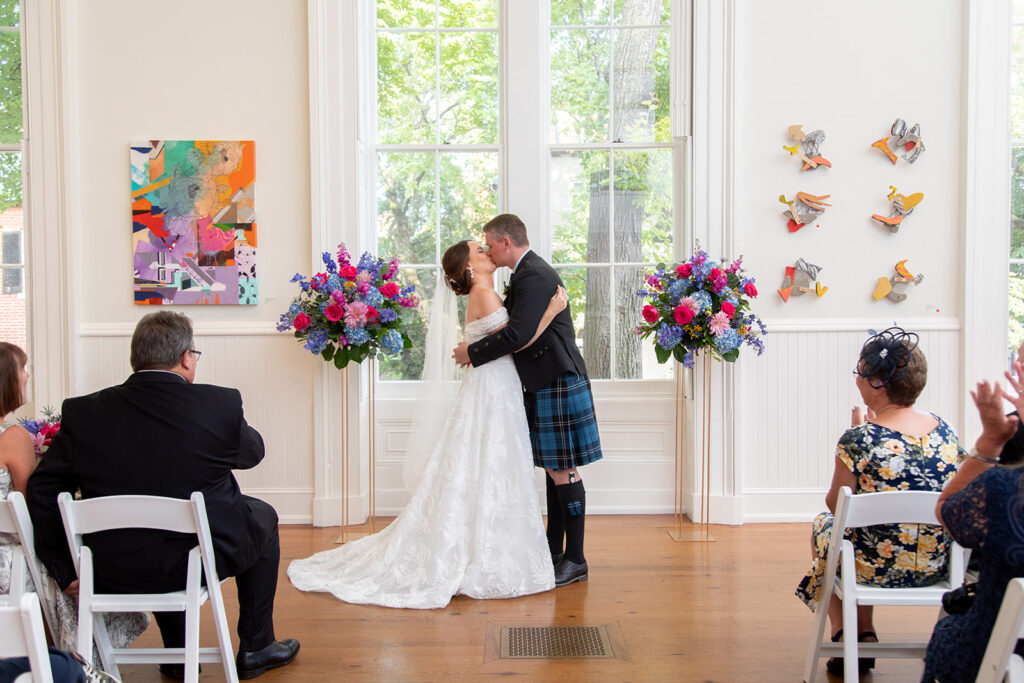 Bride and groom standing together at the altar for their first kiss during their intimate wedding ceremony at the Athenaeum in Alexandria.