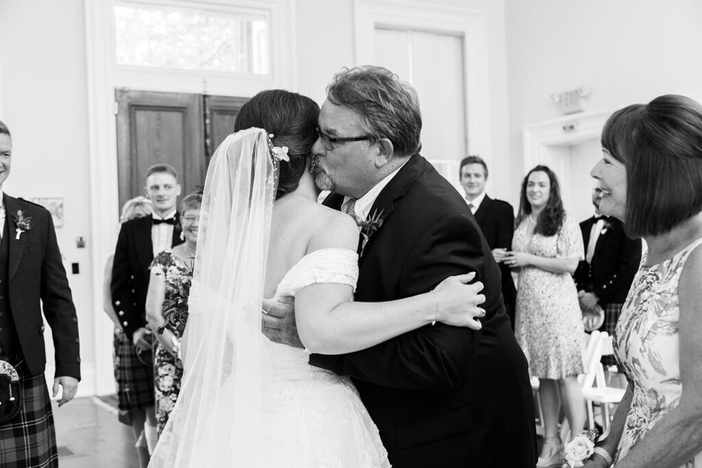 Bride sharing an emotional embrace as the father of the bride gives away the bride during the wedding ceremony at the Athenaeum in Alexandria.