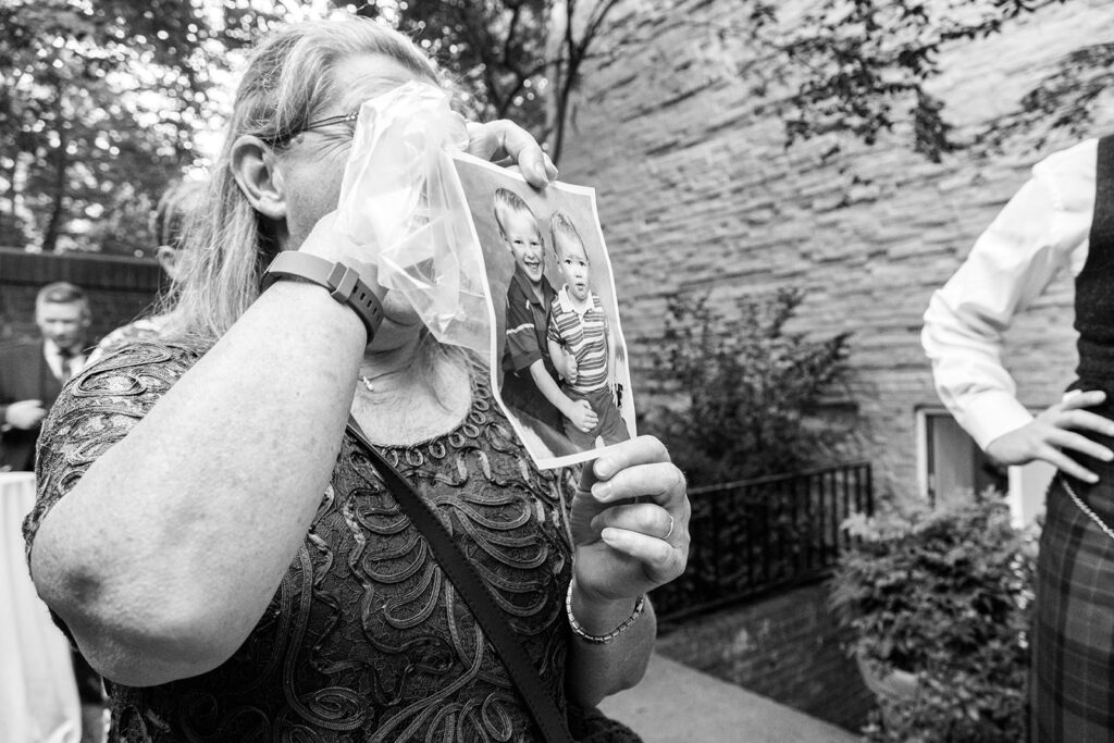 Wedding guest showing bride nostalgic childhood photo of groom as a child