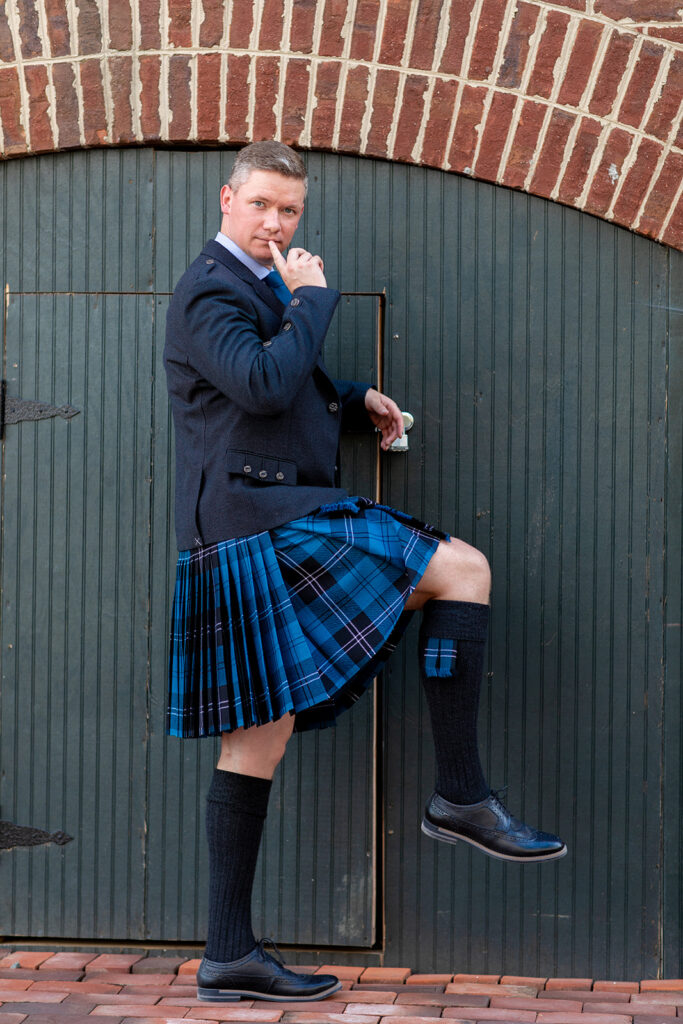 Groom posing playfully in traditional Scottish attire during downtown Alexandria wedding portraits.