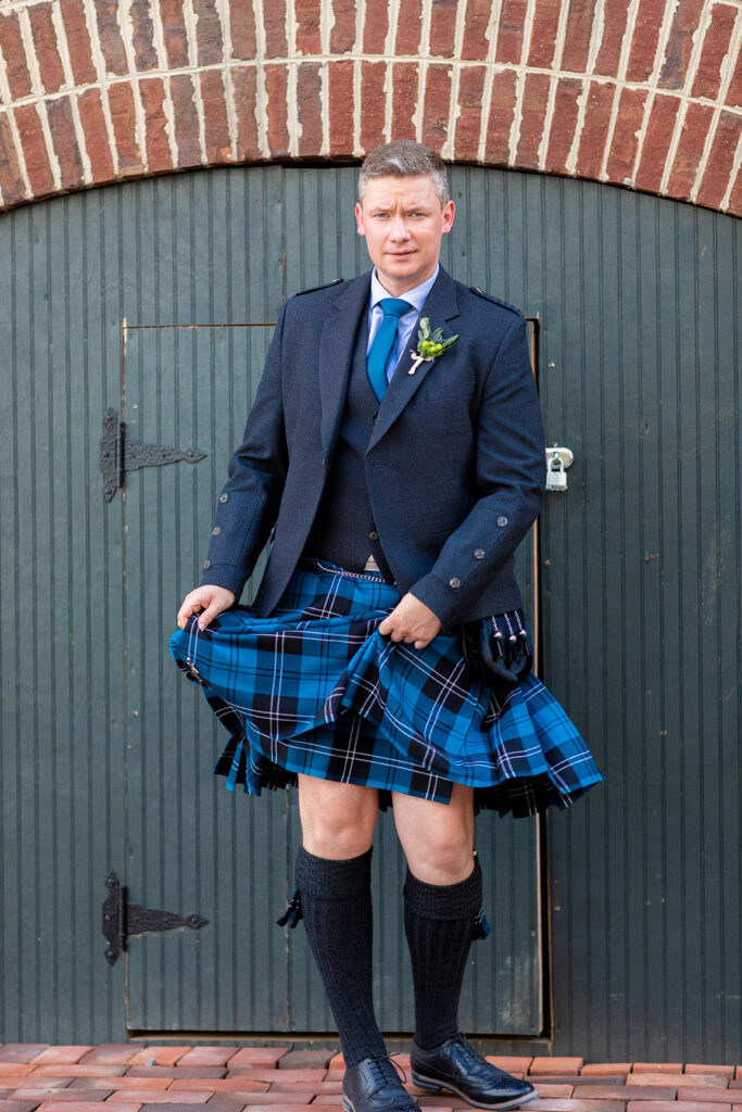 Groom playing with kilt during downtown Alexandria wedding portraits.