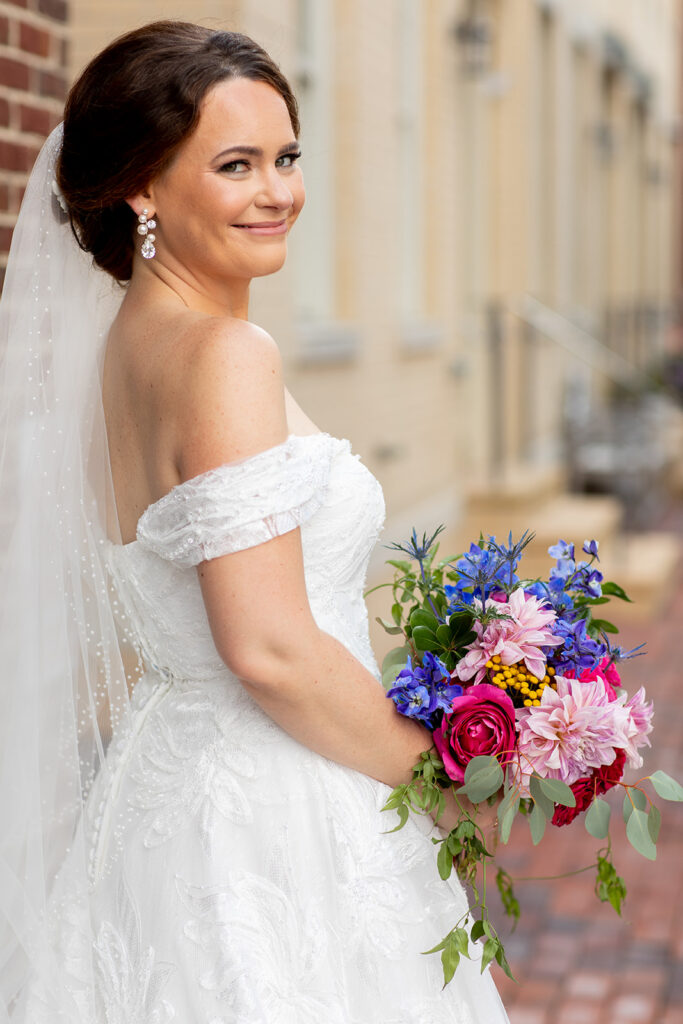 Bride smiling while holding a bouquet during downtown Alexandria wedding portraits.