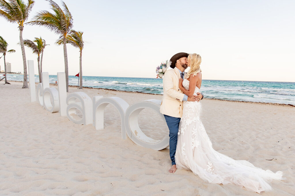 Bride and groom kissing in front of Le Blanc sign during Cancun destination wedding