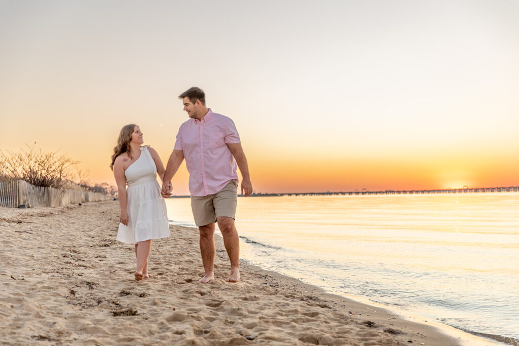 DC couple walking along the shoreline during a beach engagement session at Terrapin Nature Park