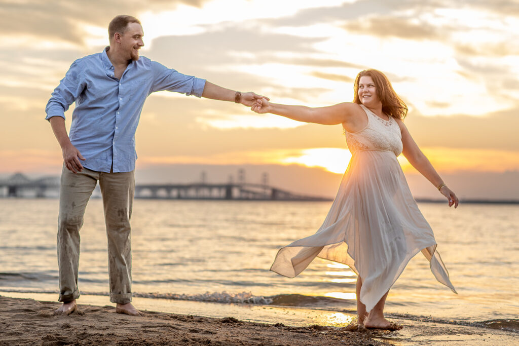 Hope and Tyler holding hands and playfully leaning away from each other at sunset along the beach at Terrapin Nature Park.