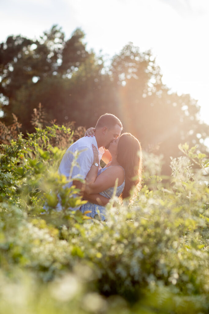 Hope and Tyler sharing a kiss in the glowing sunlight surrounded by greenery at Terrapin Nature Park during their engagement session.